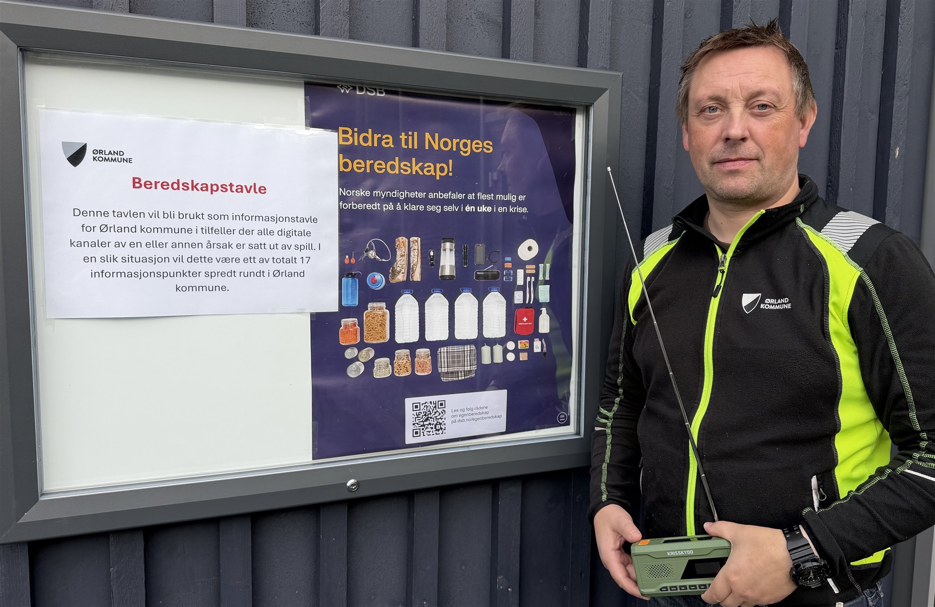 Informasjonstavle og en mann som holder en DAB-radio.